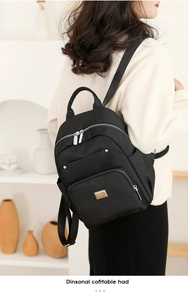 Detailed view of women black nylon backpack with multi-zipper pockets and metal logo