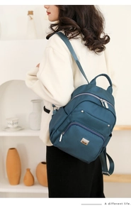 Detail view of women's deep teal fashion backpack showing adjustable straps and side pockets