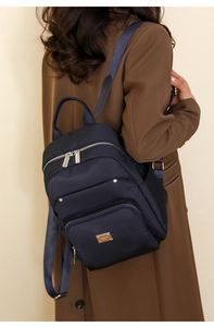 Detail view of the navy nylon backpack on a model showing side texture and silver zippers