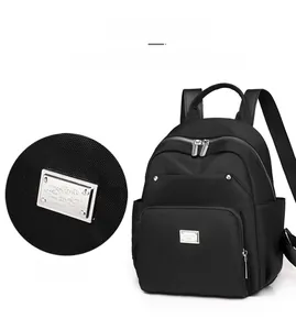 Detail of silver brand plate on black nylon backpack with textured fabric finish