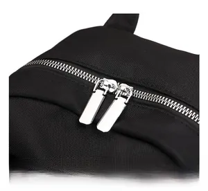 Detail showing smooth silver metal zippers and premium black fabric texture of the backpack