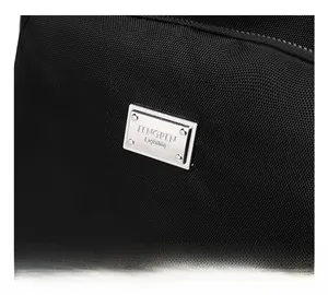 Detail shot of the rectangular silver metal logo plate on black nylon backpack