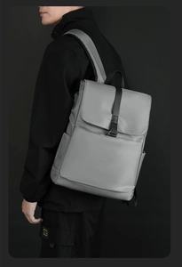 Vue latérale du sac à dos minimaliste gris clair avec boucle noire porté par un modèle