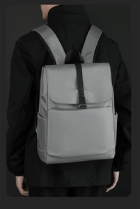 Détail d'un sac à dos gris imperméable au design minimaliste porté par un homme