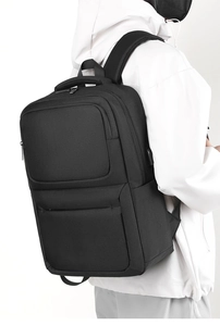 Side view of black waterproof business backpack with USB charging port on white background