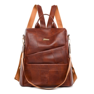 Detailed front view of brown patchwork leather backpack with metal buckle and orange straps