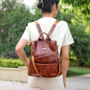 Detail of a brown PU leather backpack with patchwork texture on a female model