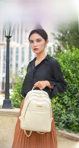Outdoor shot of a beige PU leather backpack featuring golden zippers and textured surface