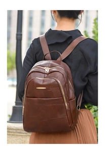 Close-up of brown PU leather backpack texture with golden zippers and stitching details