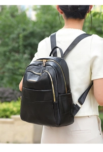 Close-up of geometric patchwork texture and golden zippers on black leather backpack