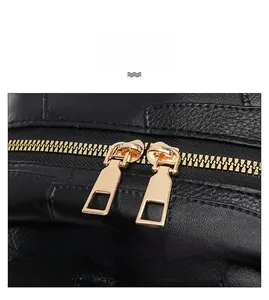 Close-up of golden dual metal zippers on black crocodile embossed faux leather backpack