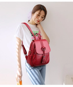 Woman wearing a dark red leather backpack with fringe pendant and woven details