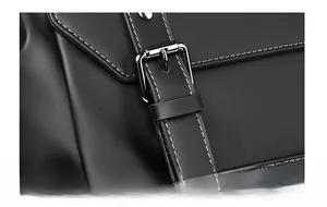 Détail du sac à dos en cuir noir mat avec boucle en métal argenté et surpiqûres blanches