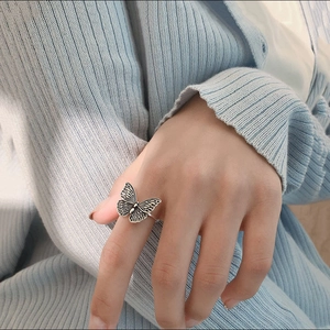 Macro detail of vintage silver butterfly ring with intricate wing patterns on model finger