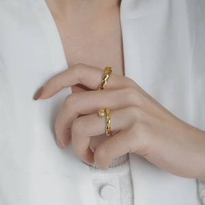Close-up of gold 925 silver stacked rings with twisted and irregular textures on model hand