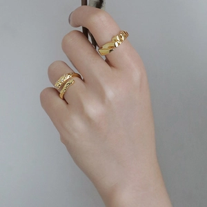 Detail of gold geometric textured ring and slim open band with sparkling zircon accents