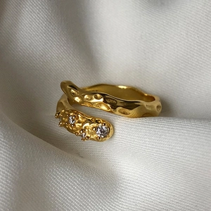 Close-up of golden ring with lava texture and three sparkling zircon accents