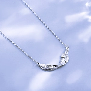 Macro detail of silver feather pendant with sparkling zircons and fine brushed texture