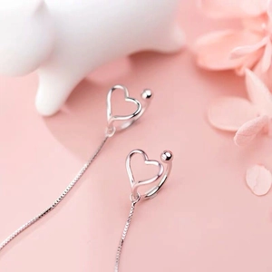 Detailed view of S925 silver hollow heart tassel earrings on elegant silk decor