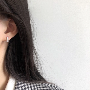 Close-up of a silver square hoop earring with pave-set zircon stones on a female model