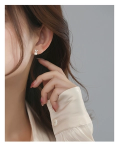 Détail d'une boucle d'oreille cœur en argent S925 avec perle et accents de diamant