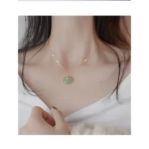 Detail of light green Hetian jade Pingan buckle pendant on a gold necklace worn by a model