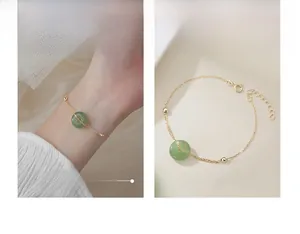 Detail of gold chain bracelet with green jade donut pendant and beads on wrist