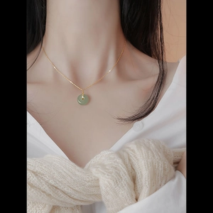 Elegant jade Pingan buckle pendant necklace on gold chain worn by a model
