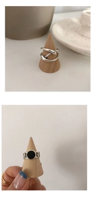Détail de bague nouée et anneau vintage avec pierre noire sur support en bois