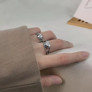 Close-up of S925 silver heart rings with woven texture and minimalist open band