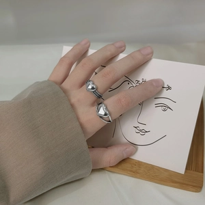 Detail of s925 silver heart rings on a model hand with minimalist art background