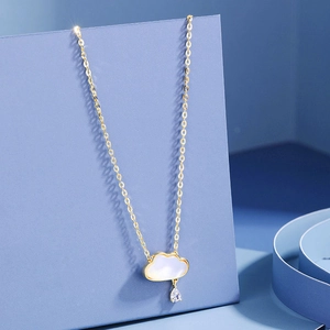 Macro detail of gold cloud pendant with mother of pearl and pear-cut zircon drop