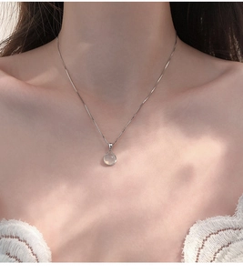 Detail of 925 sterling silver necklace with round white chalcedony pendant on a model