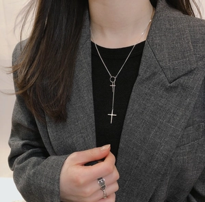 Silver Y-shaped cross necklace with dual pendants worn by a model in a grey blazer