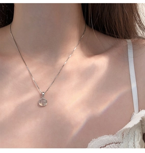 Close-up of 925 sterling silver necklace with a round white chalcedony pendant on neck
