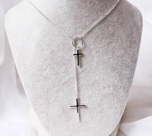Detailed view of S925 silver double cross pendant necklace on a grey jewelry display stand