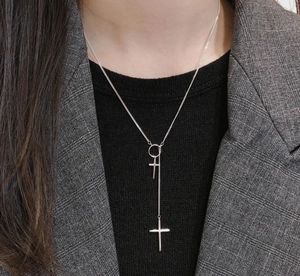 Close-up of a double cross silver necklace on a model showing the stylish lariat design