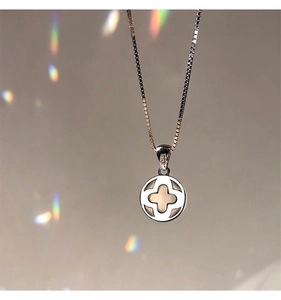 Macro detail of S925 sterling silver hollow clover pendant on box chain with rainbow light