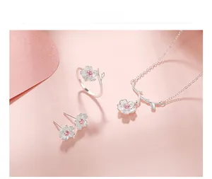 Detailed set of silver cherry blossom jewelry with pink stones on a romantic pink background