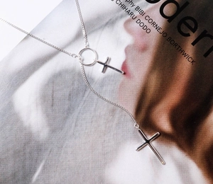 Detailed view of S925 silver Y-shaped cross necklace on a fashion magazine background