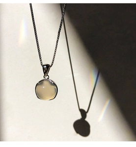 Macro shot of 925 sterling silver necklace with a round white chalcedony pendant and light refraction