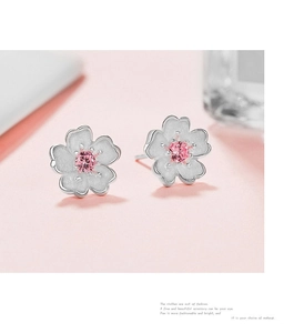 Macro detail of cherry blossom stud earrings with pink center stone and frosted petals