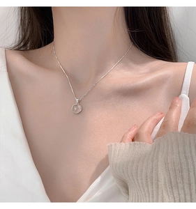 Close-up of a delicate silver necklace with a round white chalcedony pendant on a model