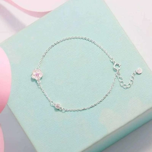 Close-up of silver-tone cherry blossom bracelet with pink petal charm and lobster clasp