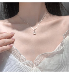 Detail of 925 sterling silver necklace with a round chalcedony pendant on a female model