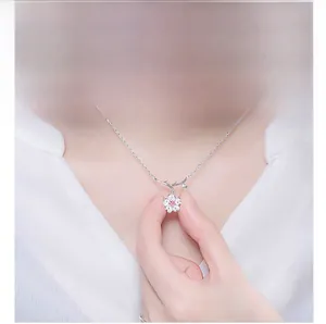 Close-up of Japanese cherry blossom necklace with pink gemstone pendant on a woman