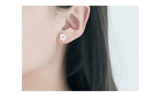 Close-up of a silver cherry blossom stud earring with a pink crystal center on ear