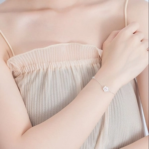 Detailed view of silver cherry blossom bracelet with pink crystal on woman's wrist