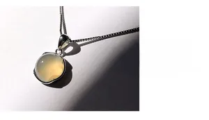 Macro shot of white chalcedony pendant on 925 sterling silver chain with artistic shadows