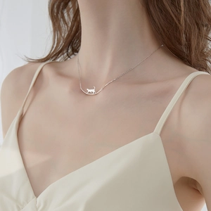 Gros plan d'un collier avec pendentif chat argenté porté par un mannequin femme